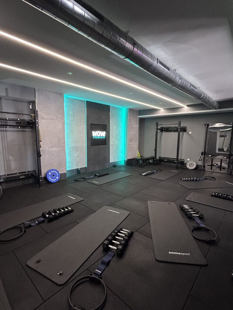 Interior de WOW! Fitness Club en Colmenar Viejo: racks de fuerza, esterillas y mancuernas listas para una sesión